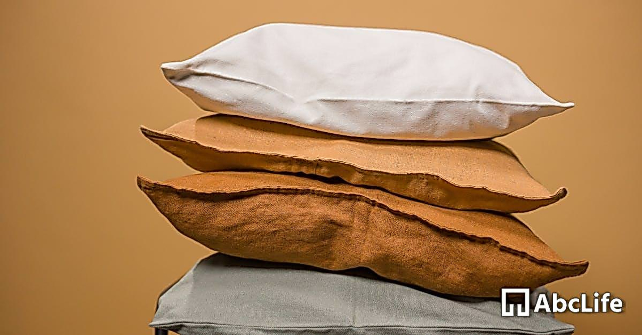 Stack of different colorful pillows folded and placed in stack on chair isolated on dark beige background