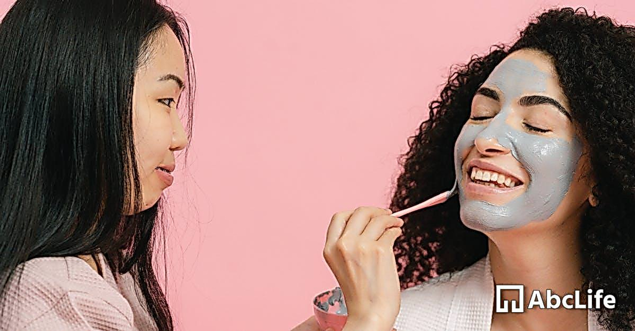 Woman putting on cosmetic mask on face of other woman