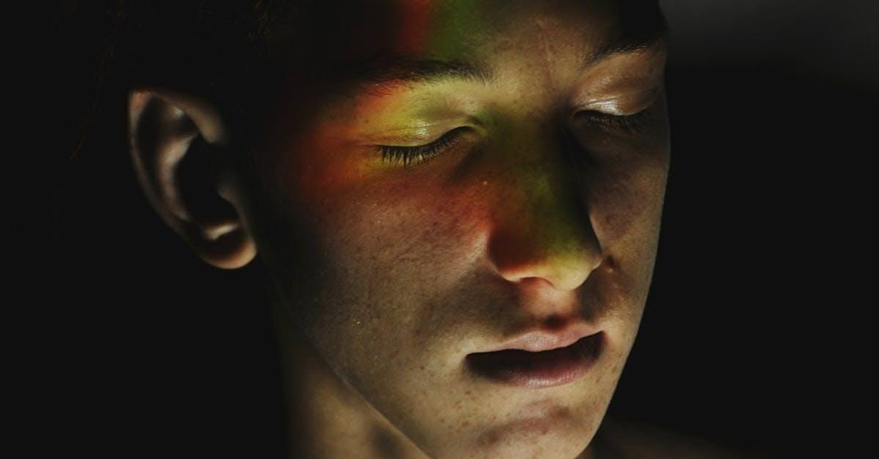 Freckled teenager with neon lights on face