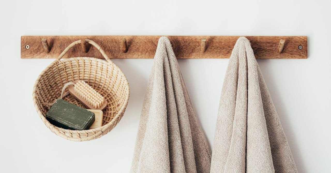 Wooden hanger with towels and basket with bathroom products